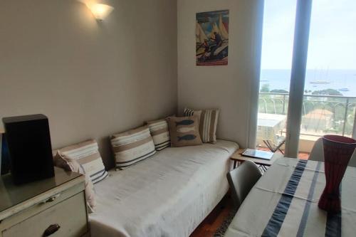 uma sala de estar com um sofá e uma grande janela em Bel appartement climatisé vue mer parking gratuit. em Villefranche-sur-Mer