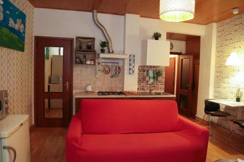 un sofá rojo en la sala de estar con cocina en Guest House Benny, en Reggio Emilia