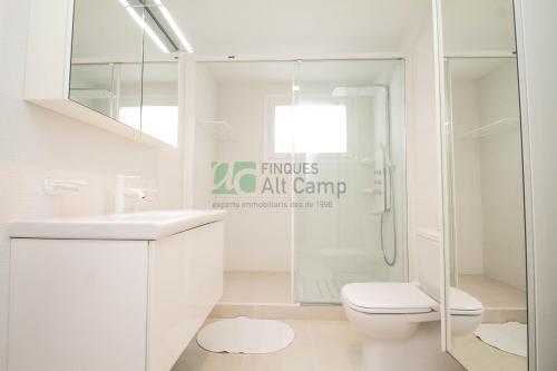 a white bathroom with a shower and a toilet at piso alto standing en Segur de Calafell in Calafell