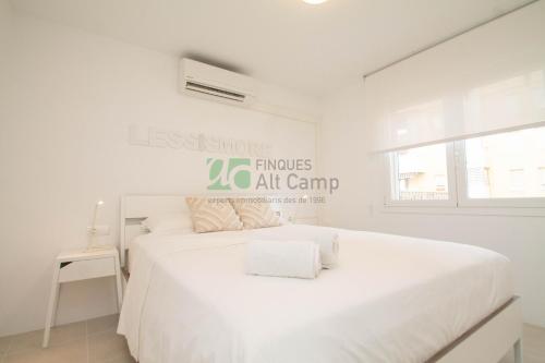 a white bedroom with a white bed and a window at piso alto standing en Segur de Calafell in Calafell