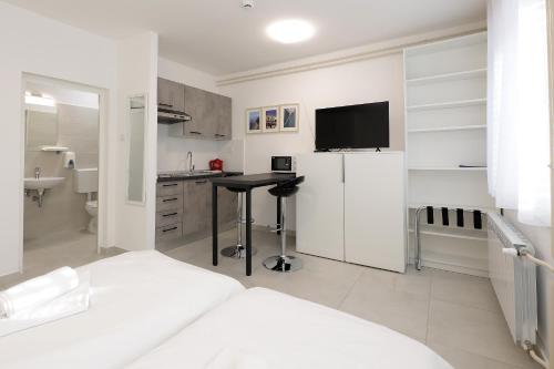 Dieses weiße Zimmer verfügt über ein Bett und eine Küche mit einem Kühlschrank. in der Unterkunft Rijeka Budget Rooms in Rijeka