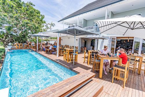 um grupo de pessoas sentadas em mesas ao lado de uma piscina em Beach Wood Boutique Hotel & Resort em Ballito