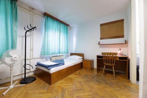 Schlafzimmer mit einem Bett, einem Schreibtisch und einem Ventilator in der Unterkunft Rijeka Budget Rooms in Rijeka