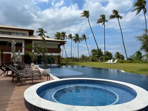 een zwembad voor een huis met palmbomen bij Apto novo Imperia Lounge pé-na-areia Itacimirim in Itacimirim