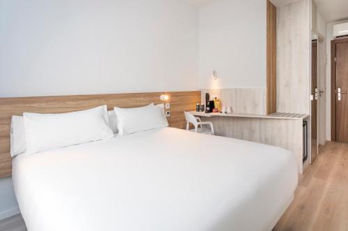 a bedroom with a large white bed and a desk at B&B HOTEL Lisboa Oeiras in Oeiras