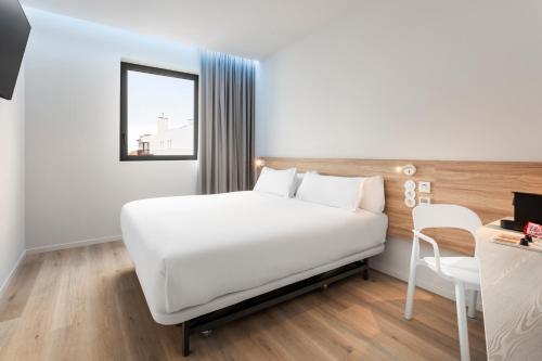 1 dormitorio con cama blanca y escritorio en B&B HOTEL Lisboa Oeiras en Oeiras