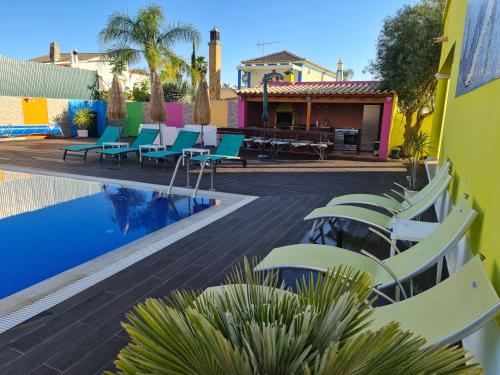 una piscina con sillas, una mesa y una casa en Villa do Lago, en Silves