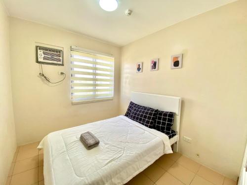 a small bedroom with a bed and a window at 2BR condo within the city! w/ Pool, WIFI & Netflix in Davao City