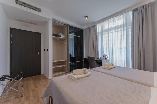 a bedroom with two beds and a large window at Sky & Sun Luxury Rooms with private parking in the garage in Zadar