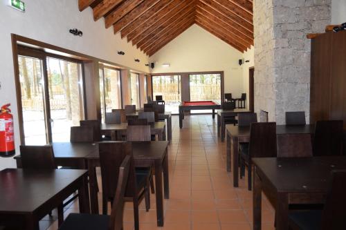 a dining room with tables and chairs and windows at Alvão Village & Camping in Reguengo