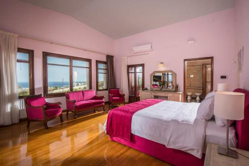 een slaapkamer met een groot bed, stoelen en ramen bij Villa Greco in Chersonissos