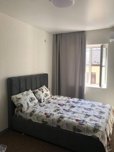 um quarto com uma cama com um edredão e uma janela em Apartment on Zarwanska Street em Kamianets-Podilskyi