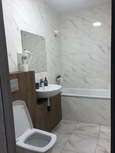a bathroom with a sink and a toilet and a tub at Apartment on Zarwanska Street in Kamianets-Podilskyi