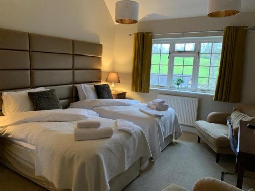 a bedroom with two beds with towels on them at Hurtwood Hotel in Peaslake