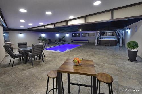 a living room with a table and chairs and a pool at סוויטת שרדונה in ‘Ein Ya‘aqov