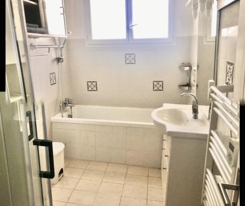 Baño blanco con bañera y lavamanos en Villa de plein pied 120m2, climatisée, 3 chambres, piscine privée, la campagne aux portes de NARBONNE, en Narbona