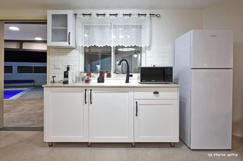 a kitchen with white cabinets and a white refrigerator at סוויטת שרדונה in ‘Ein Ya‘aqov