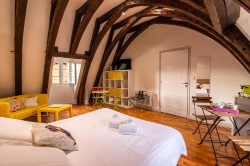 Un dormitorio con una gran cama blanca en una habitación con techos de madera. en Les Chambres du "Coup de Coeur de Sarlat" en Sarlat-la-Canéda