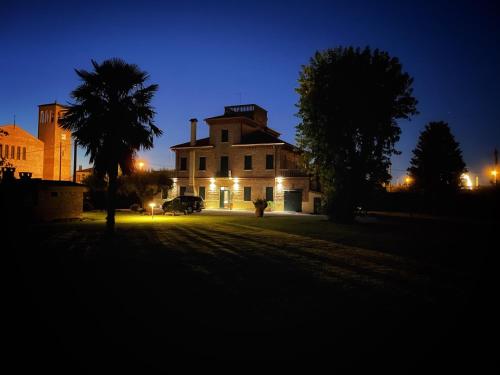 une vieille maison avec un palmier et un bâtiment la nuit dans l'établissement Villa di Charme esclusiva, à Branta