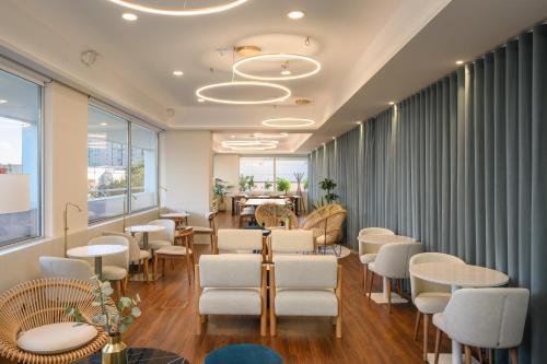 - une salle d'attente avec des tables et des chaises blanches dans l'établissement Melia Lisboa Oriente Hotel, à Lisbonne