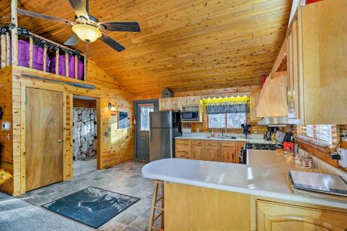 a kitchen with wooden cabinets and a ceiling fan at Cozy Manistique Cabin with Deck, Grill and Fire Pit! in Manistique