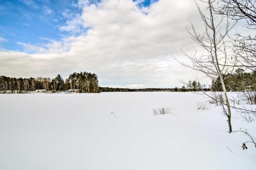 a snow covered field with trees in the background at Cozy Manistique Cabin with Deck, Grill and Fire Pit! in Manistique