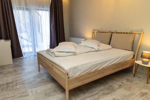 een bed met witte lakens en kussens in een kamer bij EdMont in Pietroşiţa