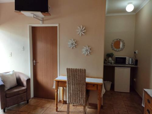 a room with a table and a chair and a television at Acacia Gastehuis in Kathu