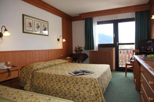 a hotel room with two beds and a window at Hotel Nigritella in Selva di Cadore
