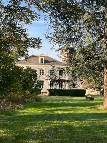 une grande maison blanche avec un arbre dans la cour dans l'établissement Domaine de Préfond, à Bengy-sur-Craon
