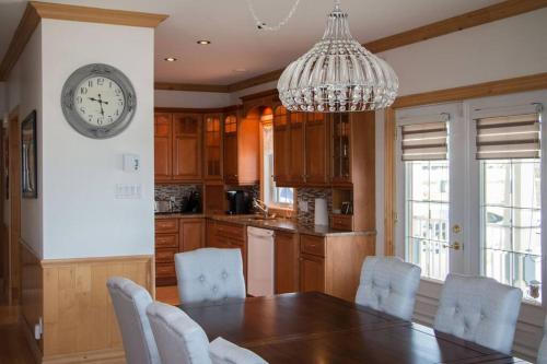 a kitchen with a dining table and a clock on the wall at Villa CARPE DIEM in Sainte-Flavie