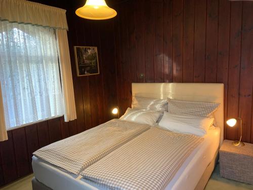 a bedroom with a white bed with wooden walls at Logierhaus Lehde in Kaupen