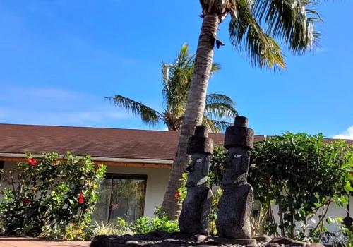 a house with a palm tree and a statue at Hotel Puku Vai in Hanga Roa