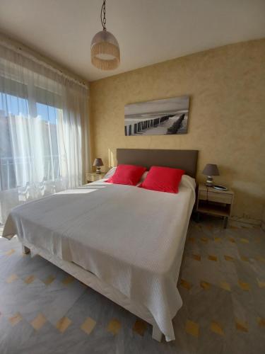 une chambre avec un grand lit blanc avec des oreillers rouges dans l'établissement Appartement Frejus Plage, à Fréjus