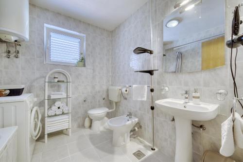 La salle de bains blanche est pourvue d'un lavabo et de toilettes. dans l'établissement Apartment Justina, à Murter