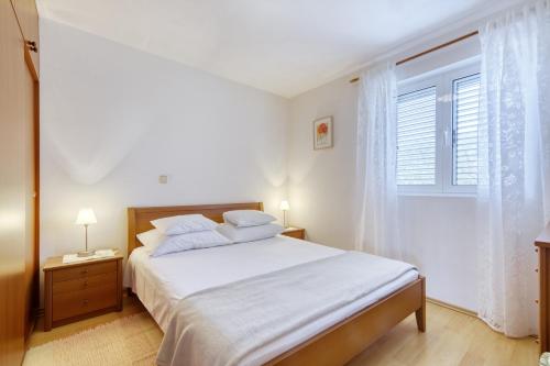 - une chambre blanche avec un grand lit et une fenêtre dans l'établissement Apartment Justina, à Murter