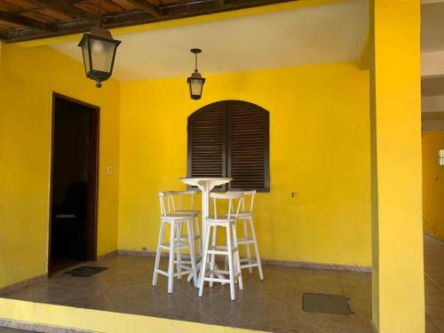 a yellow wall with stools and a table in a room at Casa Temporada Cabo Frio in São Pedro da Aldeia