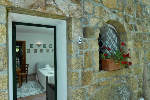 un muro di pietra con finestra e una pentola di fiori di Lu Pastruccialeddu a Arzachena