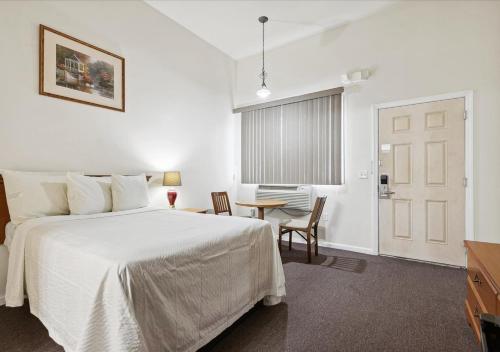 1 dormitorio con 1 cama blanca, mesa y sillas en Edison Motor Lodge, en Edison