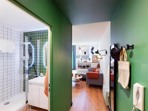 une salle de bains avec un mur vert et un salon dans l'établissement Résidence Kley Angers, à Angers