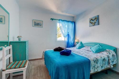 - une chambre avec un lit doté d'une couverture bleue et d'une chaise dans l'établissement Costa Isora, à Puerto de Santiago