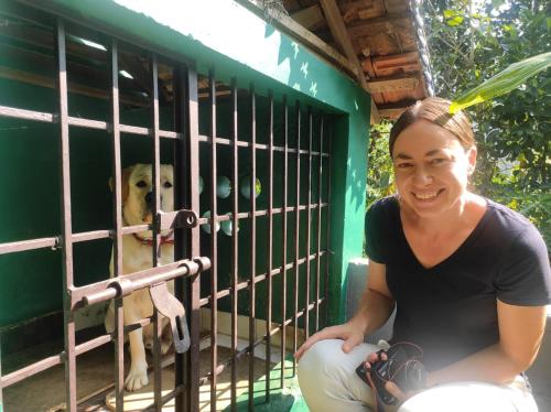 a woman sitting next to a dog in a cage at Thoppil Homestay Munnar in Munnar