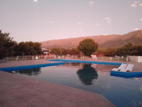 una piscina con 2 sillas blancas en el agua en Complejo El Peregrino en Cortaderas