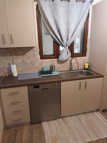 uma cozinha com um lavatório e uma janela em Perimenis Seaside House em Yerolimin