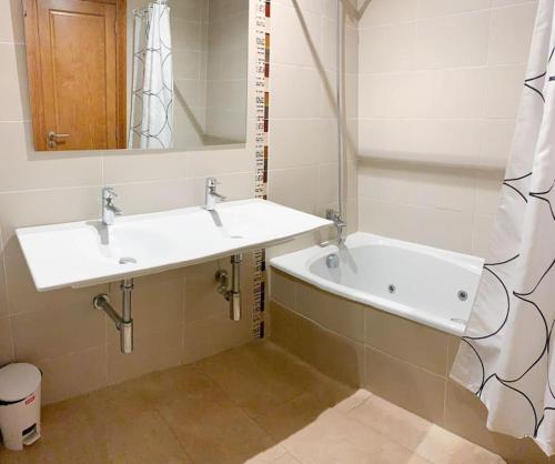 Apartamento Alcocebre Beach Resort في الكوسيبري: حمام مع مغسلتين وحوض استحمام