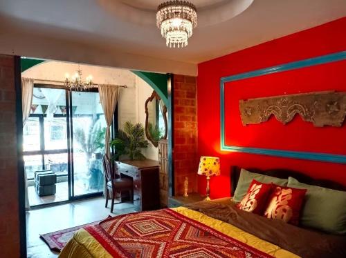 a bedroom with a red wall with a bed and a desk at Fluid PHUKET in Ban Sam Kong