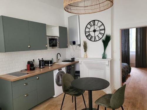 une cuisine avec une table et des chaises et une horloge au mur dans l'établissement Appartement moderne calme et spacieux-Centre Thuillat, à Limoges