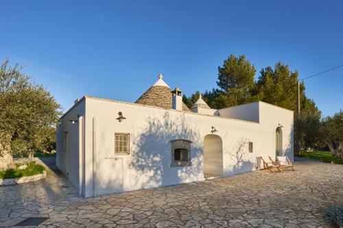 una vista exterior de un edificio blanco con árboles en el fondo en Trulli OraziO en Monopoli