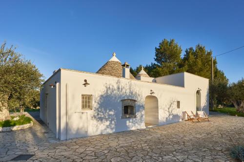 an external view of a white building with trees in the background at Trulli OraziO in Monopoli