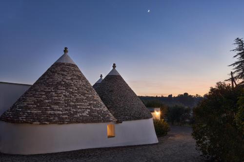 due tetti di paglia di un edificio con tramonto sullo sfondo di Trulli OraziO a Monopoli